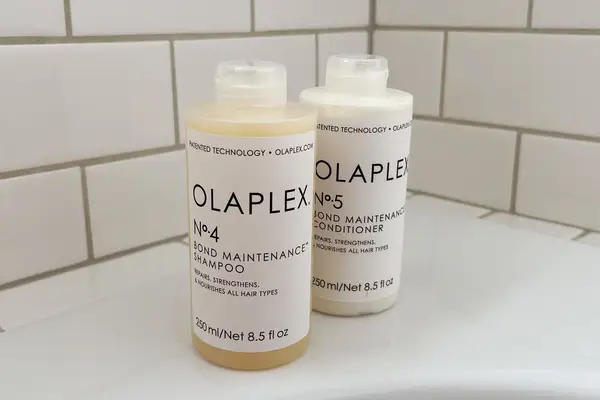 Bottles of Olaplex No. 4 Bond Maintenance Shampoo and Conditioner on the edge of a bathtub