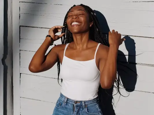A smiling woman with long hair standing with the sun on her face 