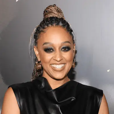 tia mowry wearing blonde knotless braids in a half-up, half-down look