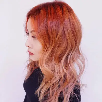 Side view of woman with scarlet to peach ombre hair