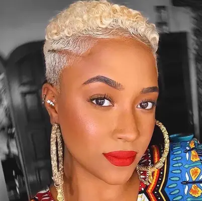 Woman with curly platinum pixie cut with shaved sides