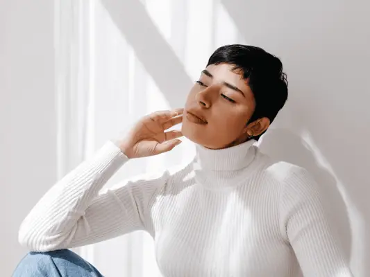 A woman with dark hair and a pixie cut wearing a white turtleneck