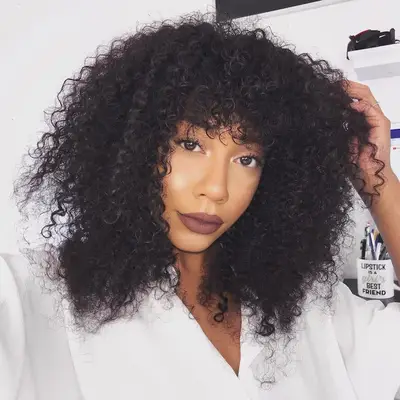 Woman with a long, voluminous curly shag hairstyle with bangs