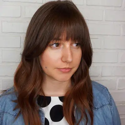 Woman with a long, feathered hairstyle with blunt bangs
