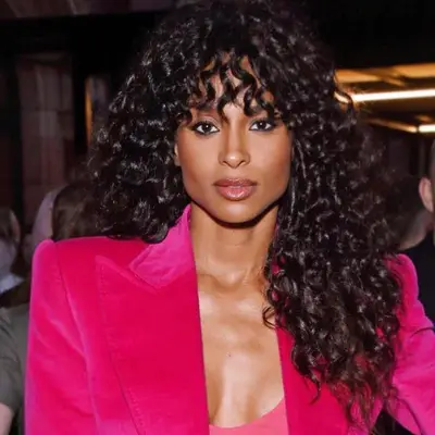 Ciara wears long, naturally curly hair with bangs