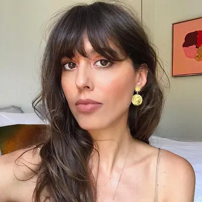 Violette wears long, wavy hair with tousled bangs