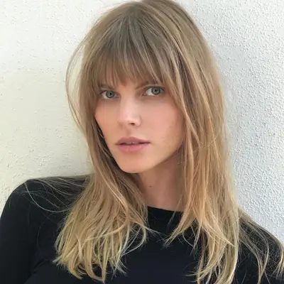 Woman with straight, highlighted blonde hair with bangs
