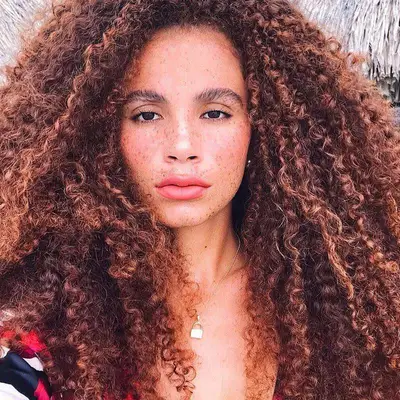 Joyjah Estrada wears her natural brunette curls with warm-toned highlights