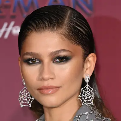 Zendaya with a slicked-back hairstyle and spider web earrings at the 2021 