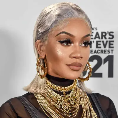 Saweetie with a platinum slicked-back hairstyle, large gold hoops, and layered necklaces at the 2021 Dick Clark