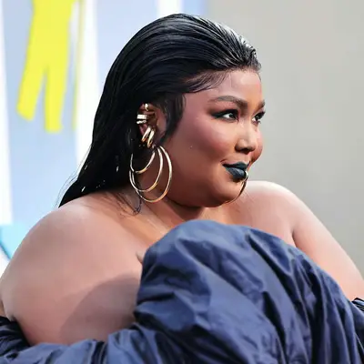 Lizzo with a wet slicked-back hairstyle and gold jewelry to the 2022 MTV VMAs in Newark, New Jersey