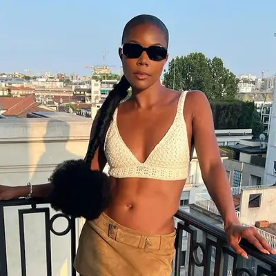 Gabrielle Union wears a braided ponytail with puffed end, sunglasses, and white crochet crop top