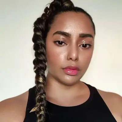 Creator wears a radiant makeup look and a high braided ponytail with highlights and gold accents