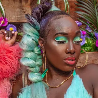 Creator with ponytail braid with teal extensions and matching eyeshadow