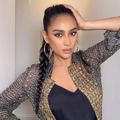 Shay Mitchell wears a volumized ponytail braid and gold earrings