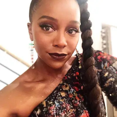Aja Naomi King wears a jumbo ponytail braid with highlights and bejeweled dangle earrings
