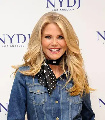 Christie Brinkley with long blonde feathered hair wearing denim jacket and neck scarf