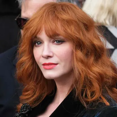 Christina Hendricks with red curly shag and bangs at Dame Vivienne Westwood