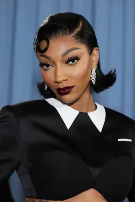 Angel Reese smizes against a blue background at the 2025 Met Gala.