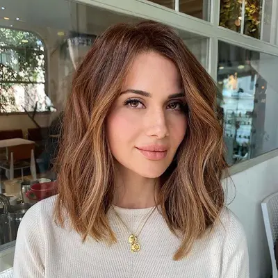 Woman with tousled brunette long bob hairstyle with caramel highlights