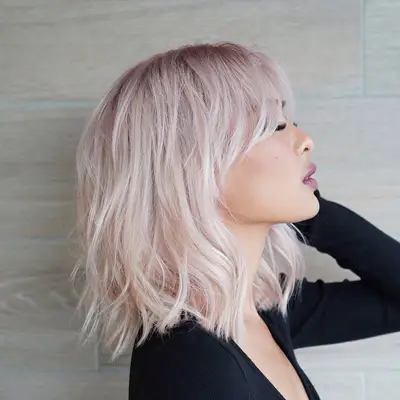 Side view of woman with pastel pink long bob hairstyle with curtain bangs