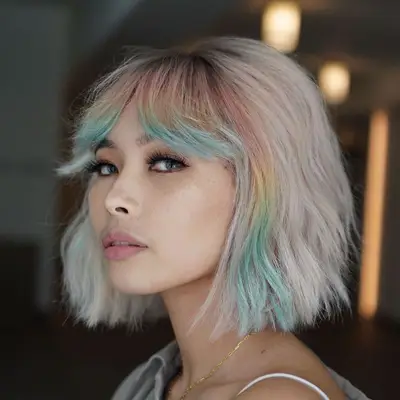Woman with platinum bob hairstyle with rainbow face-framing pieces and bottleneck bangs