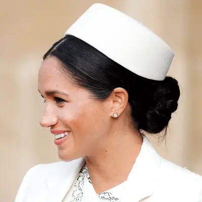 meghan markle wearing braided low bun with white hat