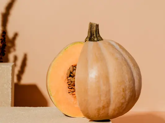 Close up of a pumpkin, partially sliced open, with a few visible seeds