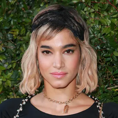 Sofia Boutella wears a wavy long bob hairstyle with side-swept baby bangs and black lace headband