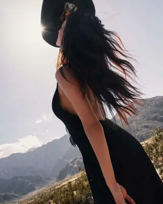 woman with long hair and cowboy hat and black halter dress in desert