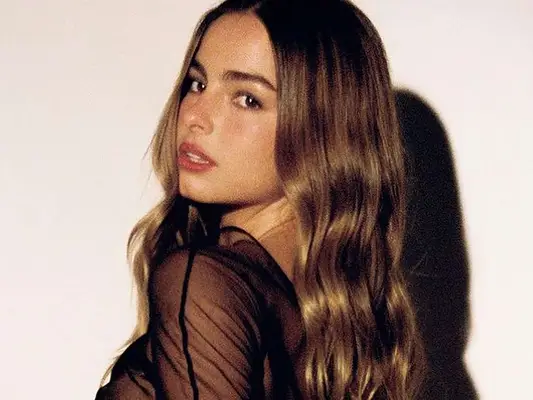 Singer Addison Rae looking over her shoulder, hair long and shiny