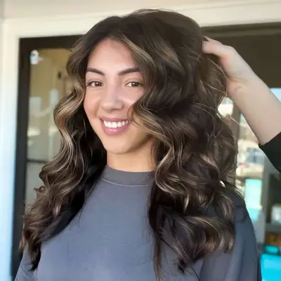 Woman with brunette hair with light honey-colored balayage.