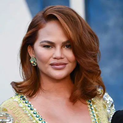 Chrissy Teigen wore a deep heavily curled side part with her copper balayage hair color against lime green, jewel adorned attire for the Vanity Fair red carpet