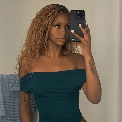 Justine Skye taking a selfie in the mirror, wearing an off-shoulder top