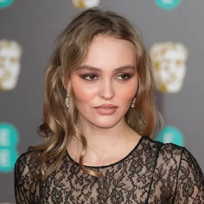Lily-Rose Depp wears curled mushroom brown hair with bronze makeup