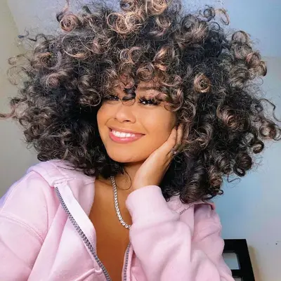Woman with natural curls and mushroom brown highlights