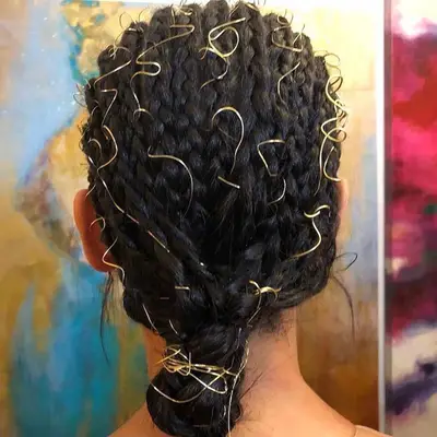 Rear view of a braided hairstyle with gold wire details throughout 