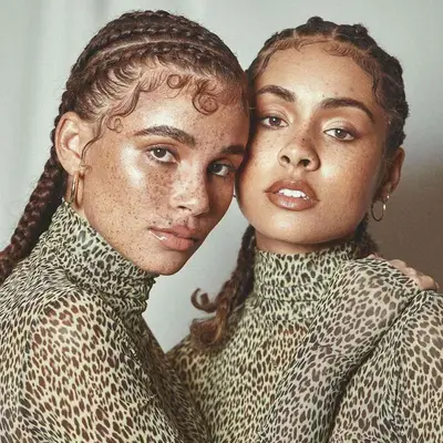 Close up of two women with cornrows, their baby hairs laid in dramatic swooping designs