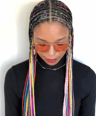 Close up of model Adwoa Aboah, her hair in straight back cornrows with plaits at her ears