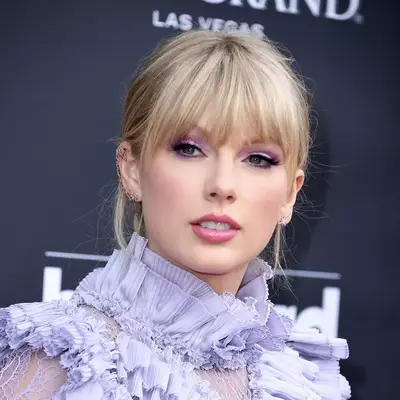 taylor swift posing with lavender gown and blonde bangs