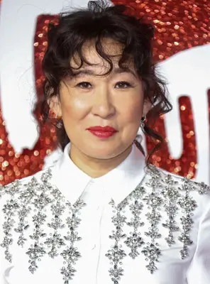 Sandra Oh curly wispy bangs updo in white blingy shirt