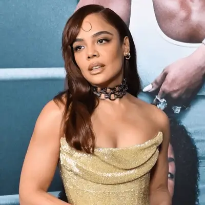 Jessica Biel with brow grazed bangs, glossy brow waves in front of blue wall