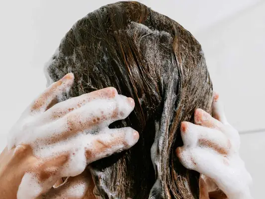 woman lathering shampoo in hair