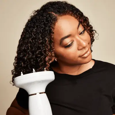 Close up of a MYM Beauty editor diffusing the ends of her curly hair.