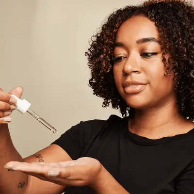 Close up of a MYM Beauty editor using an oil dropper.