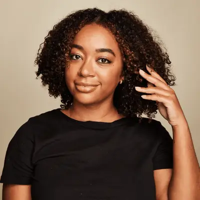 Close up of a MYM Beauty editor brushing her curly hair back with her fingers.