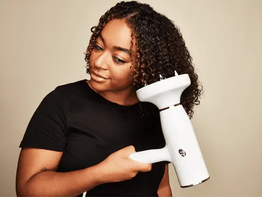 Close up of a MYM Beauty editor using a white T3 diffuser to blow dry her curly hair.