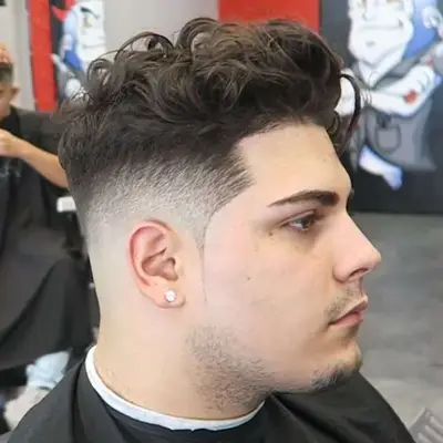 Side view of man with bald fade haircut with voluminous curly top and ice pick sideburns