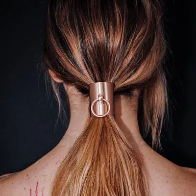 Tousled low ponytail hairstyle with statement accessory at base