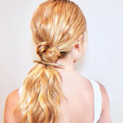 Kat McNamara wears a wavy blonde low ponytail with fastening pin